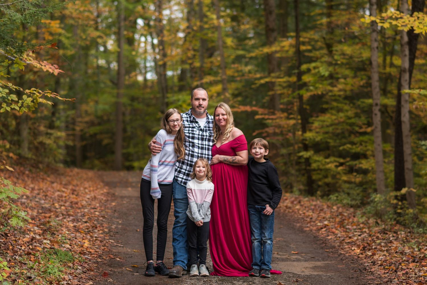 Family walking together on an autumn path surrounded by fall foliage.