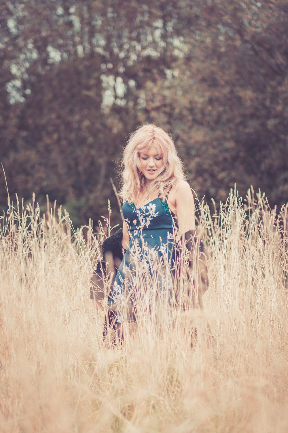 A portrait on a young woman with blonde hair in amongst tall golden grasses in Aberystwyth. Aberystwyth Portrait Photographer.