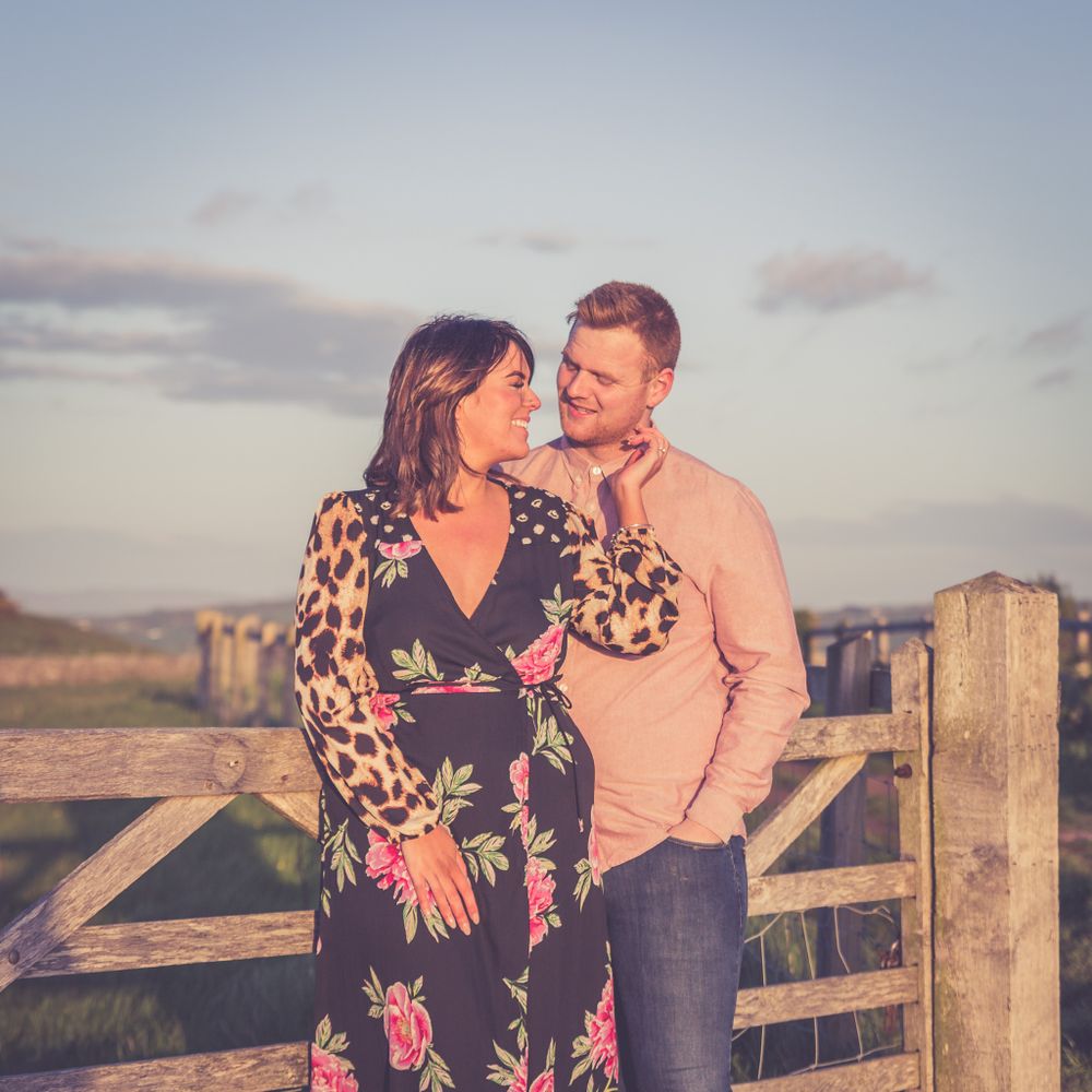 A portrait of  loving couple by a wooden gate at golden hour. North Wales Engagement Photography