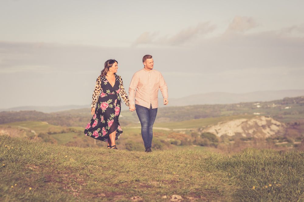 A portrait of a couple walking through fields on the North Wales coast at golden hour in summer. North Wales Portrait Photographer