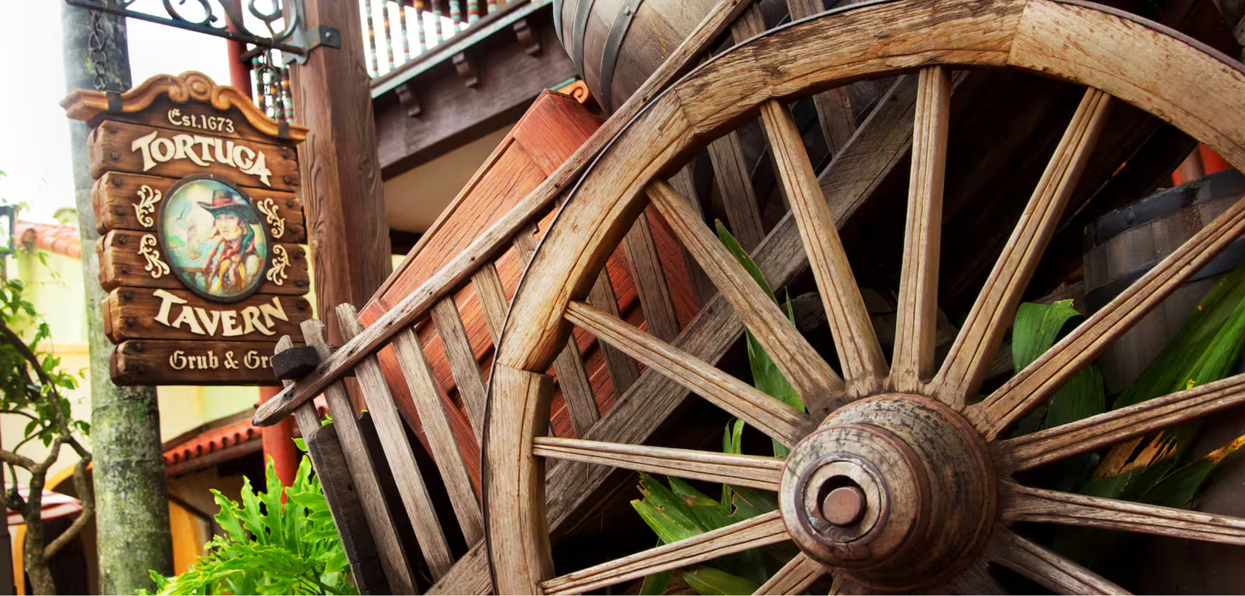 Rustic wooden wagon wheels and farm equipment mounted on a weathered barn wall create a vintage countryside display.