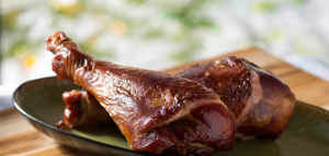 Close-up view of glazed BBQ chicken legs on a platter with rich sauce and caramelized coating.