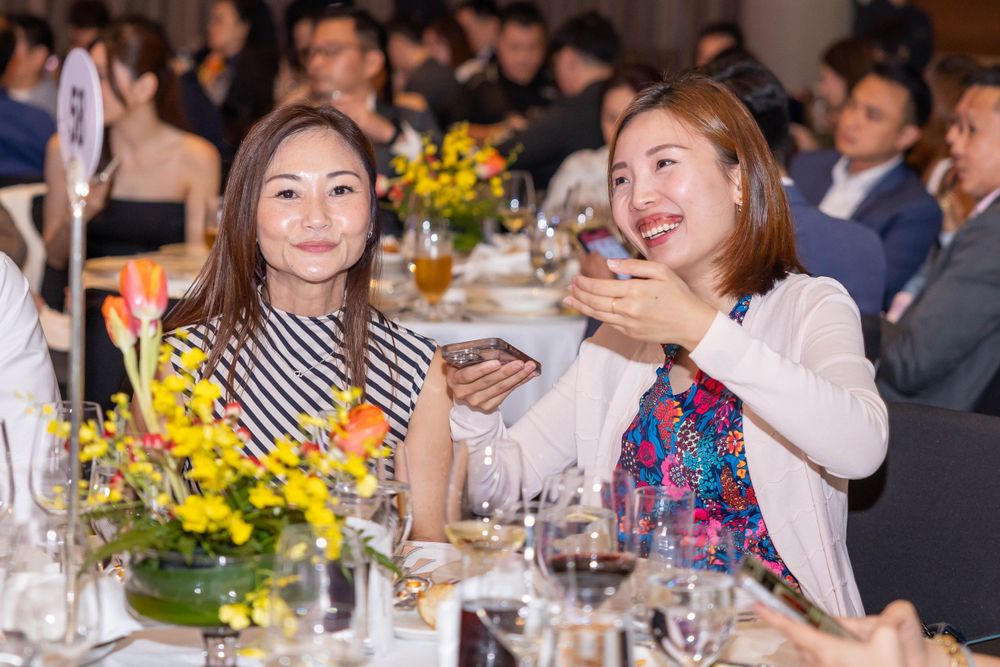 Elegant dinner party with yellow floral centerpieces and guests enjoying conversation.