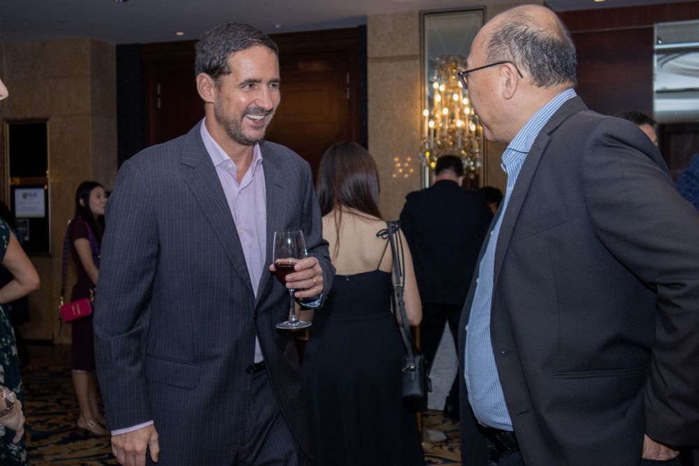 Two professionals having an animated conversation at an indoor networking event.