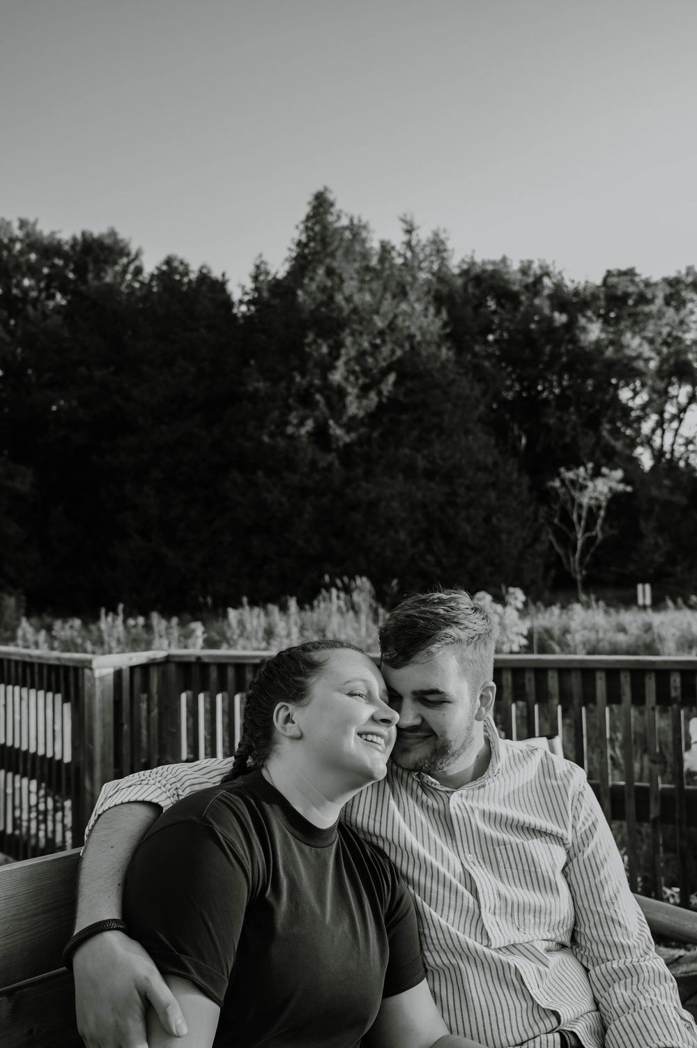 A black and white photo of a couple sharing a tender moment while sitting on an outdoor deck.