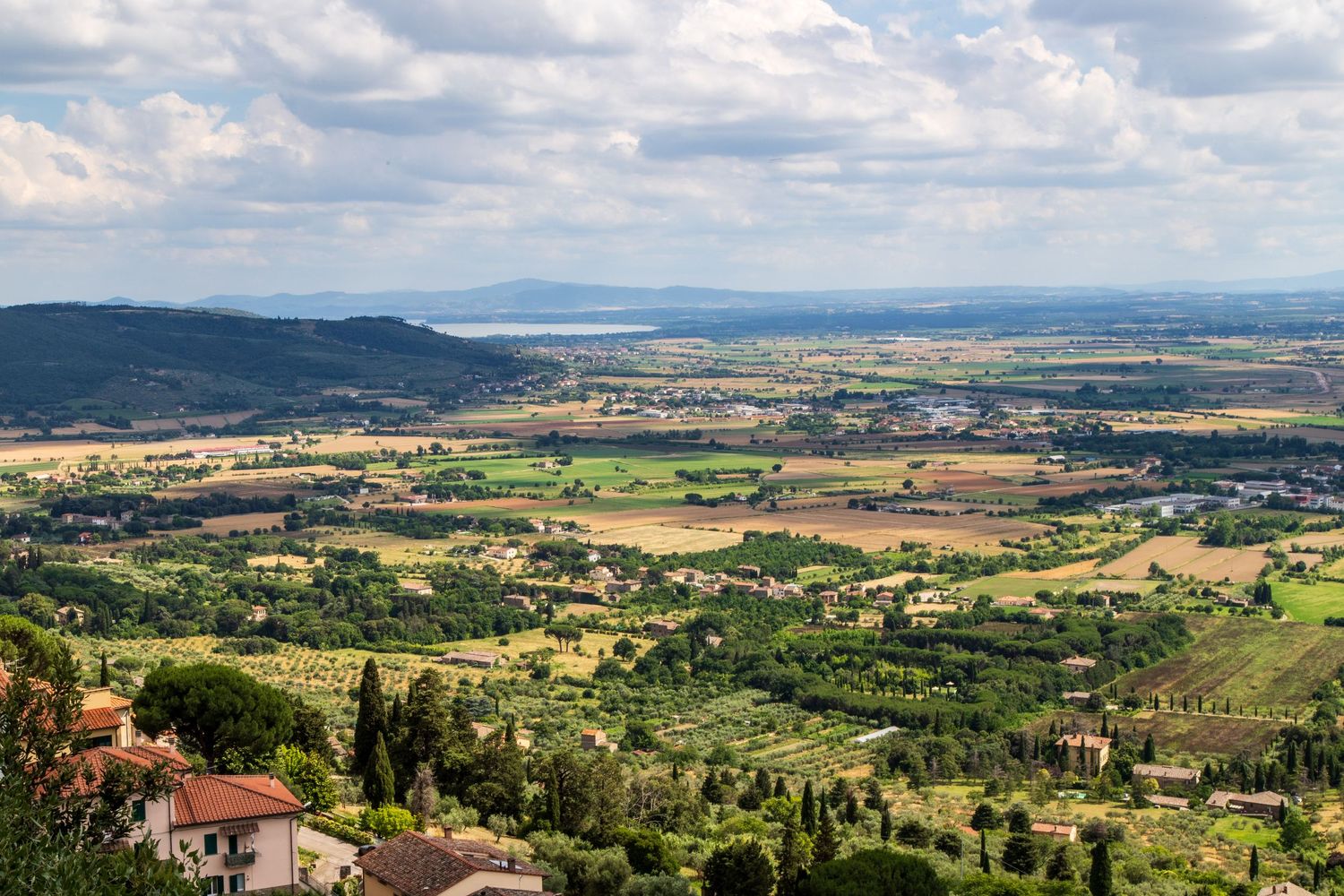 Panoramic landscape view of Italian countryside with hills, farms and distant mountains.
