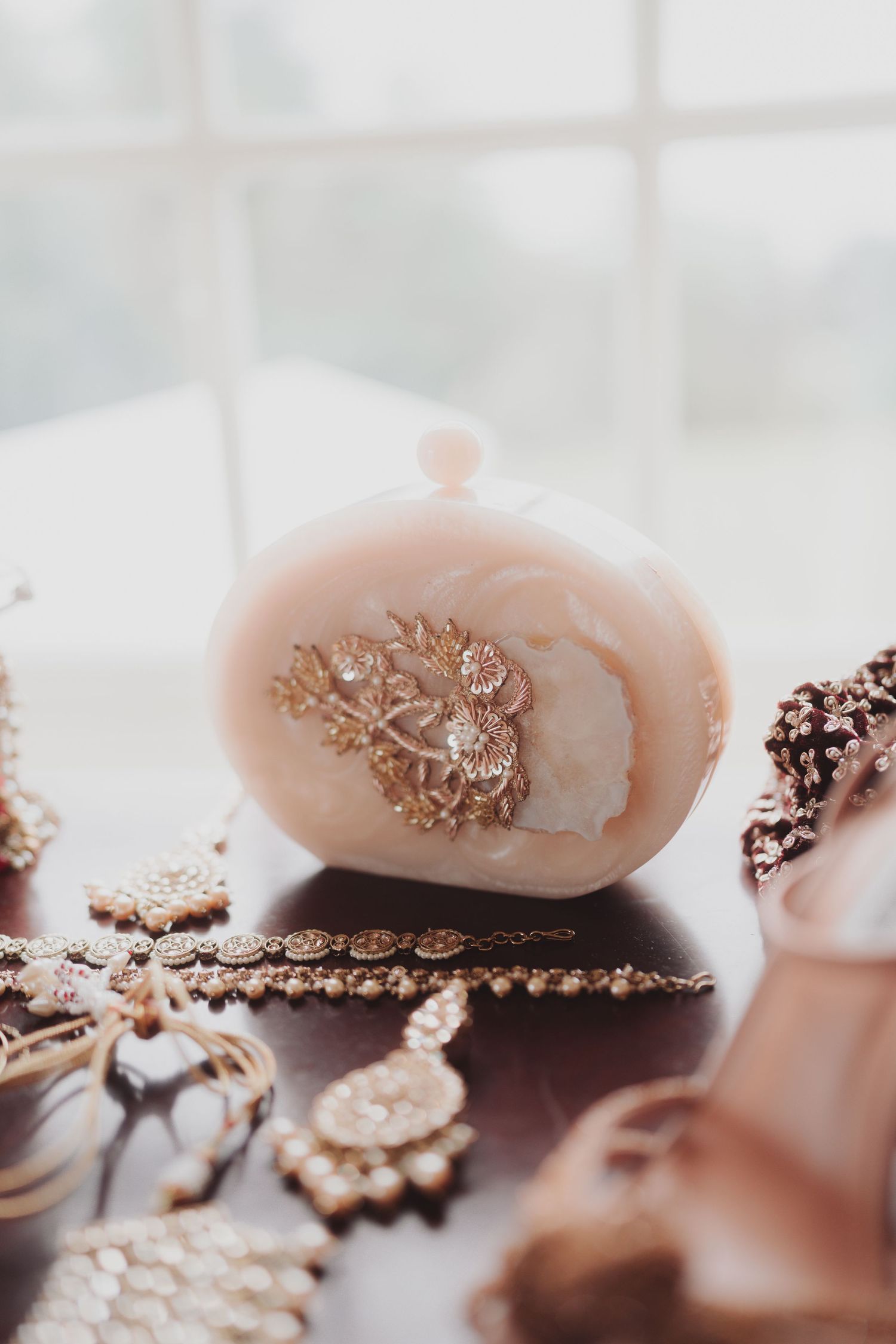 Vintage-style pink decorative ornament with delicate floral embellishments on a light surface.