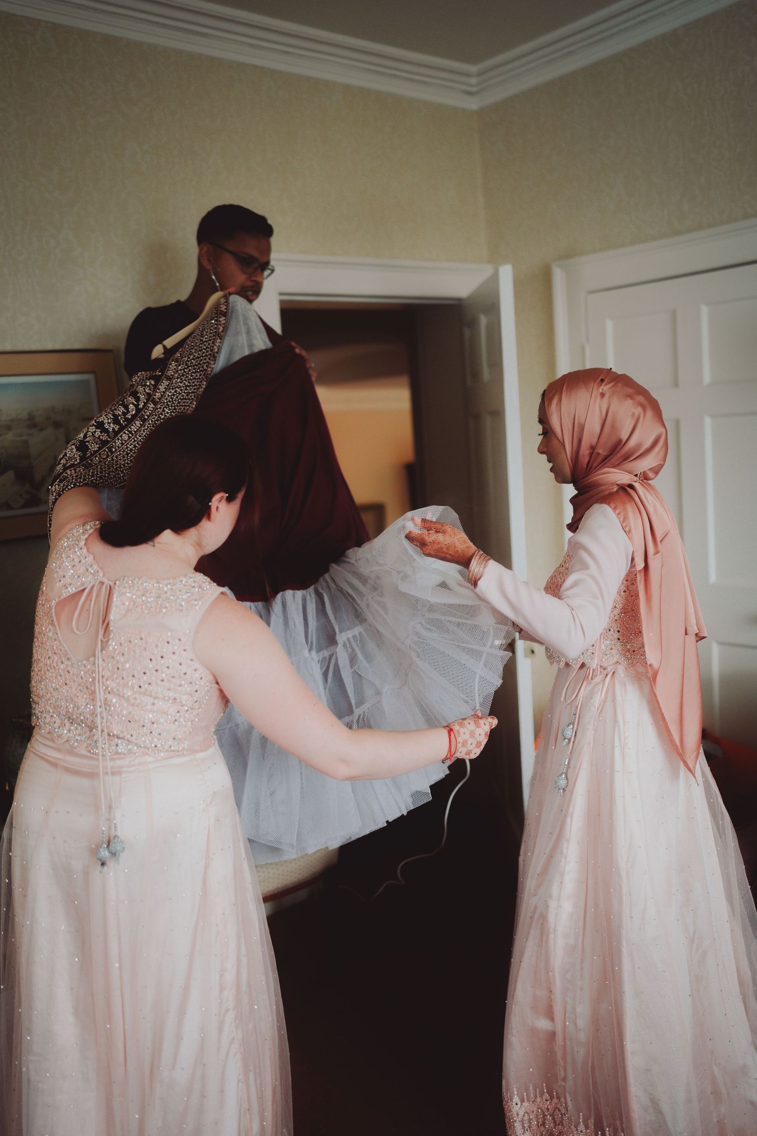Wedding preparation scene with flowing white dress being arranged.