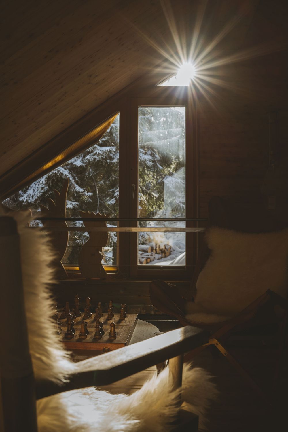 Sunburst through attic window overlooking snowy mountain landscape.