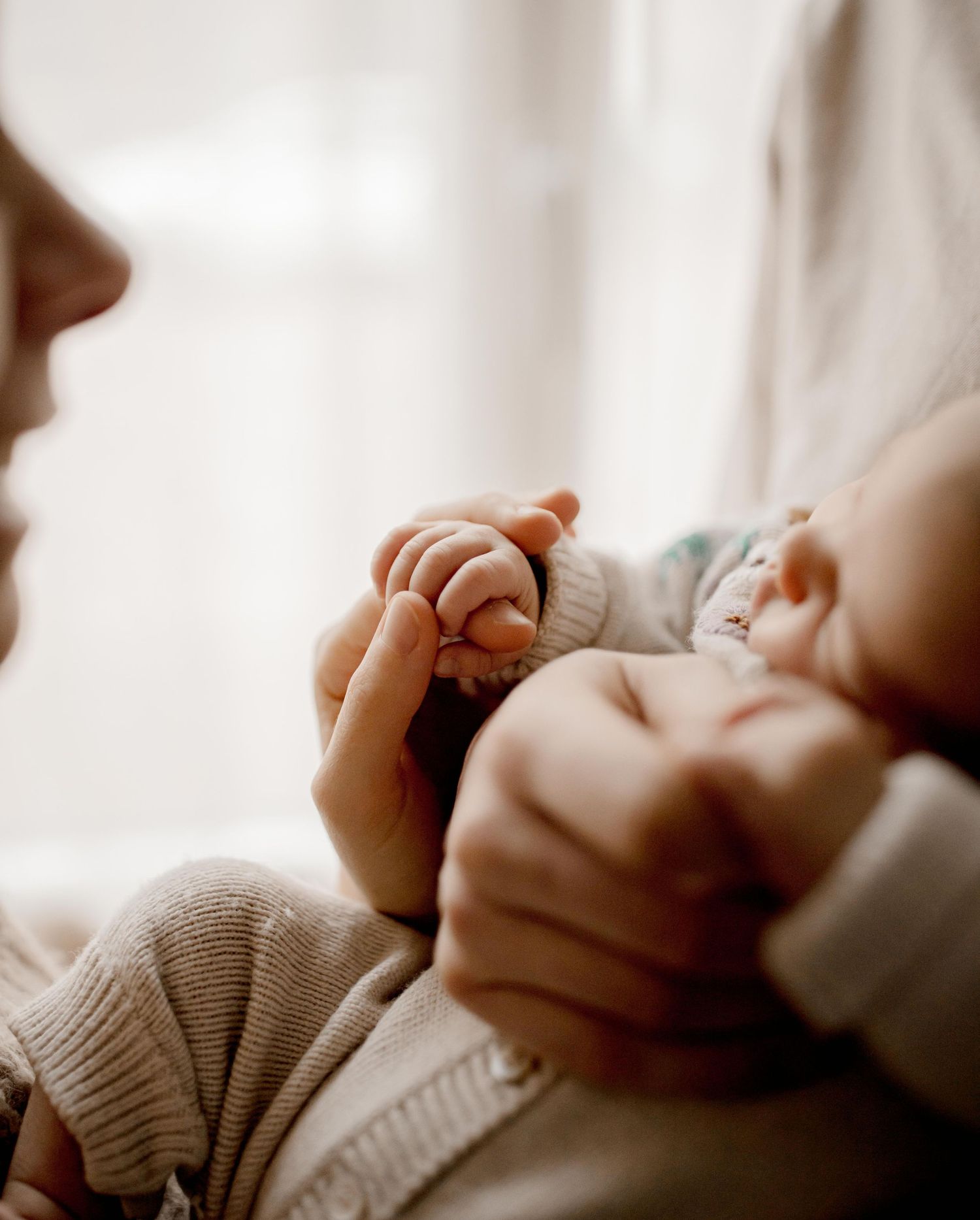 Moment de douceur entre parent et bébé dans la douce lumière du matin.