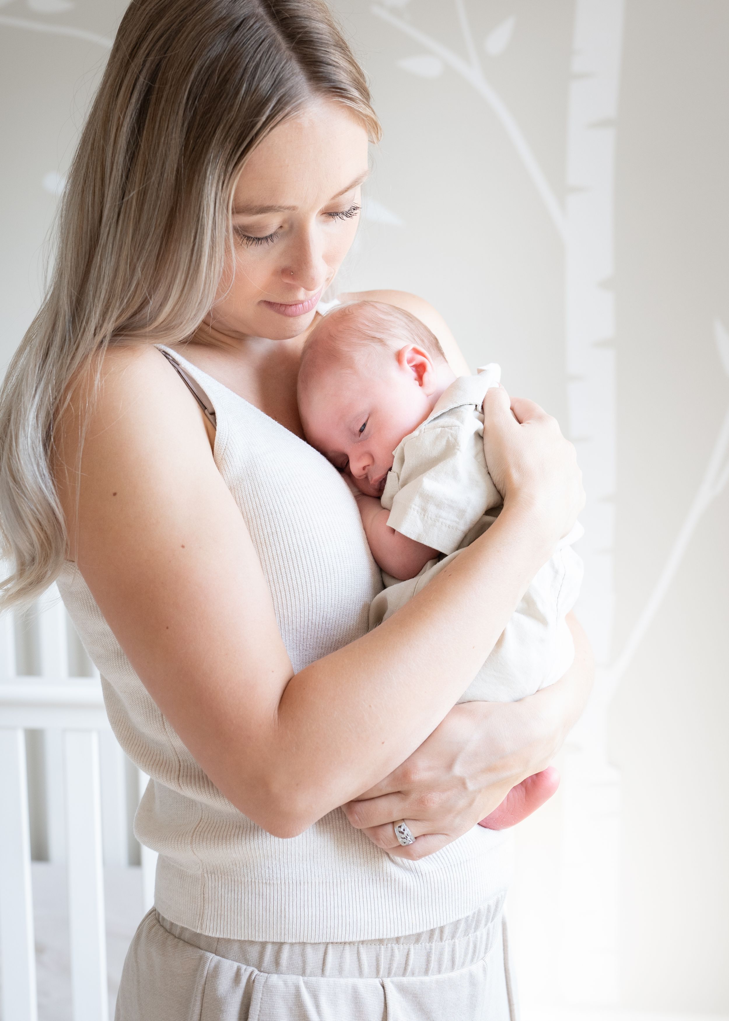 Tender moment of parent and newborn child bonding in a bright, minimalist nursery setting.