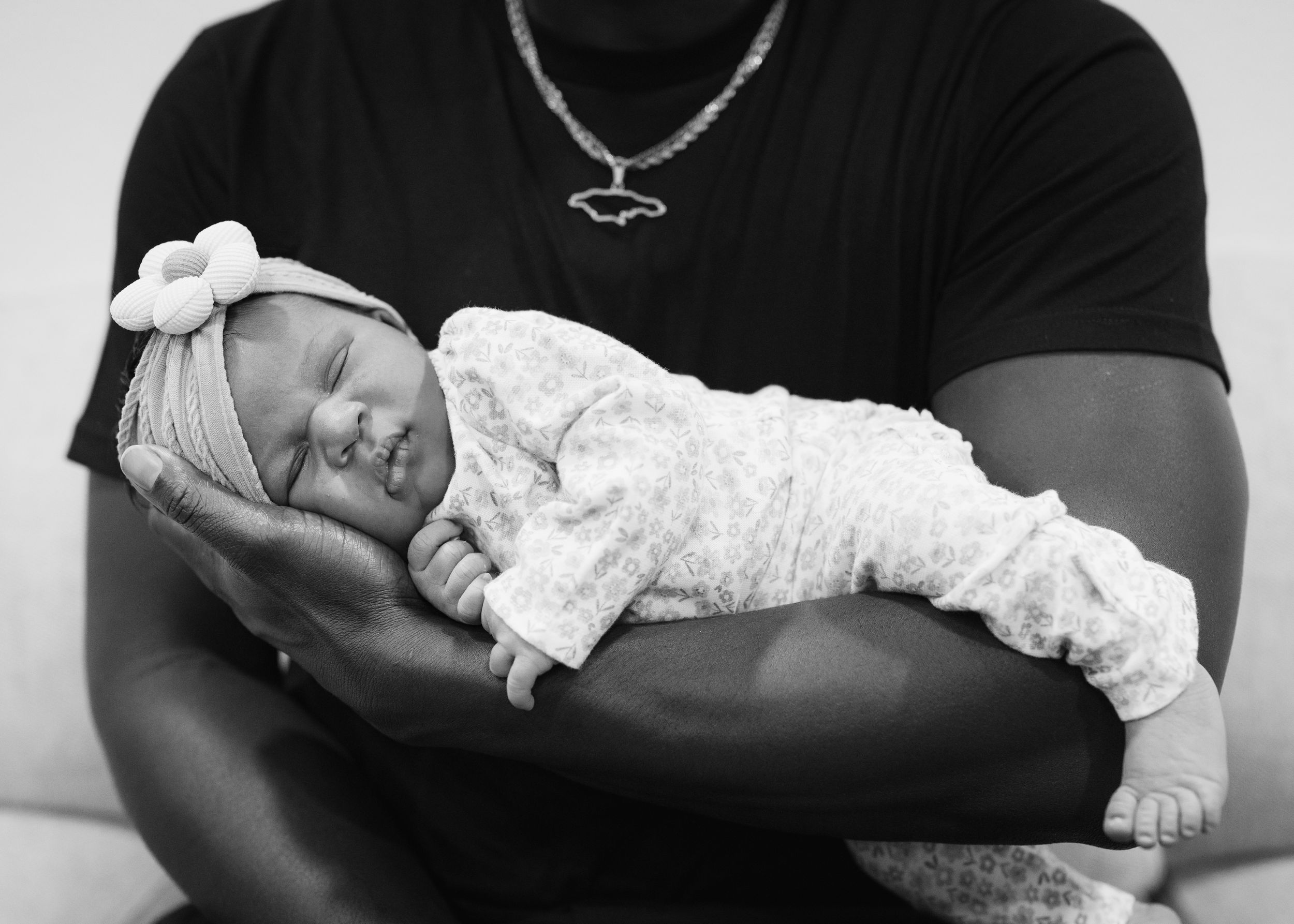A series of black and white photos showing a newborn baby sleeping peacefully in someone's arms.