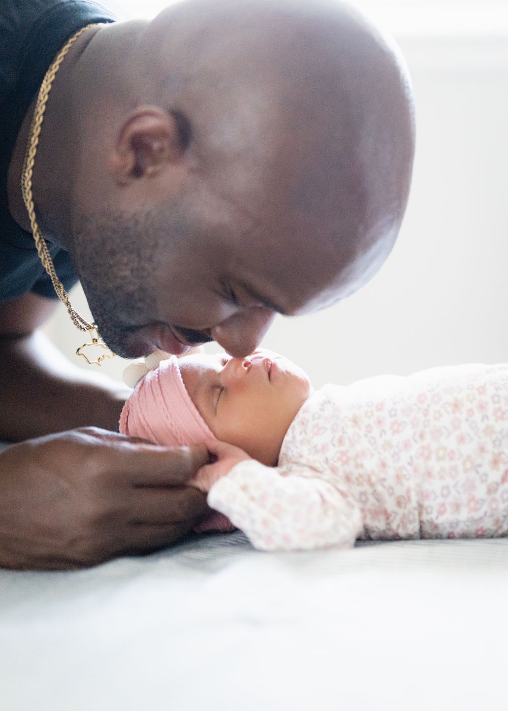 A tender moment showing someone gently kissing a baby's tiny hand against a soft white background.