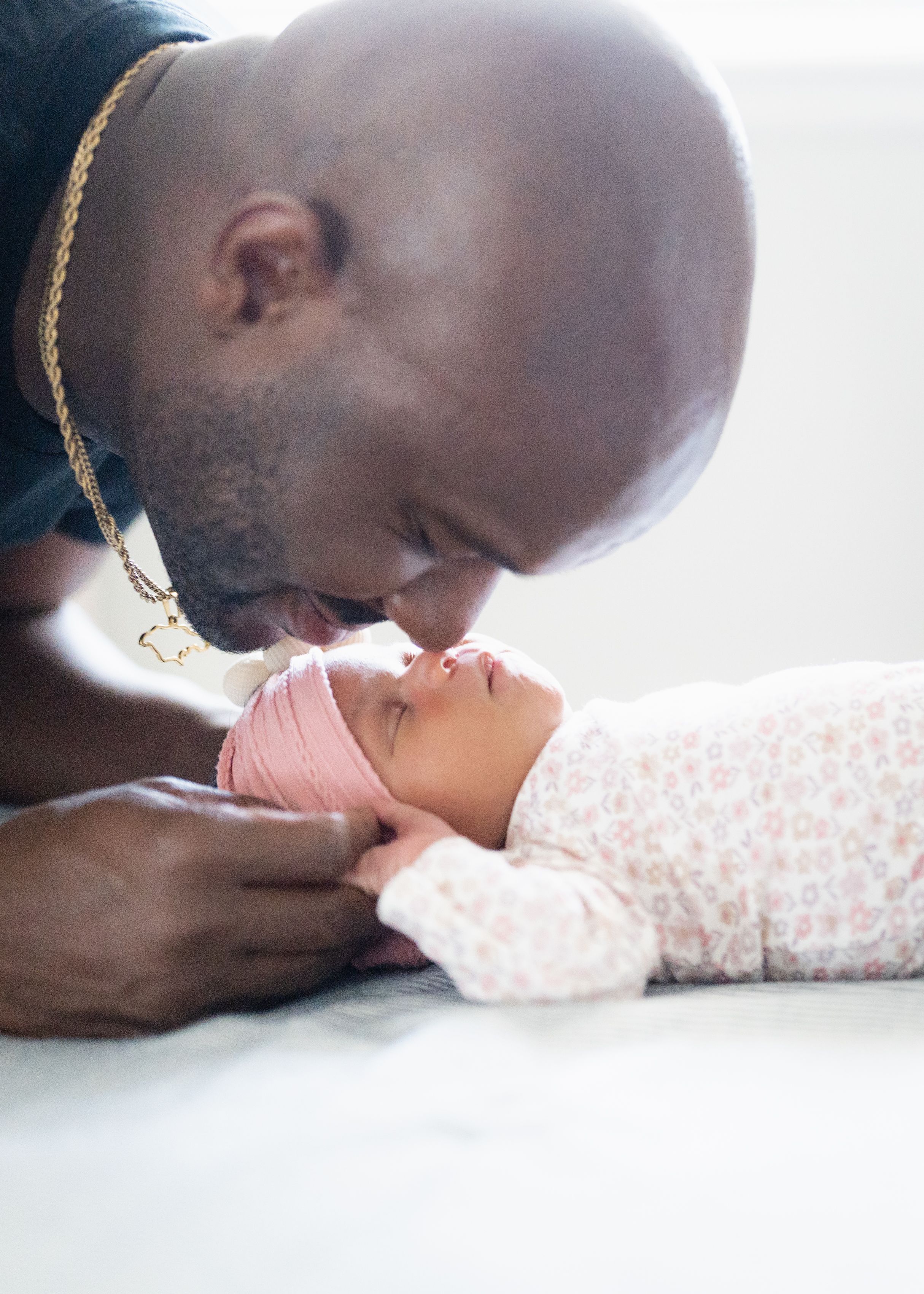 A tender moment showing someone gently kissing a baby's tiny hand against a soft white background.