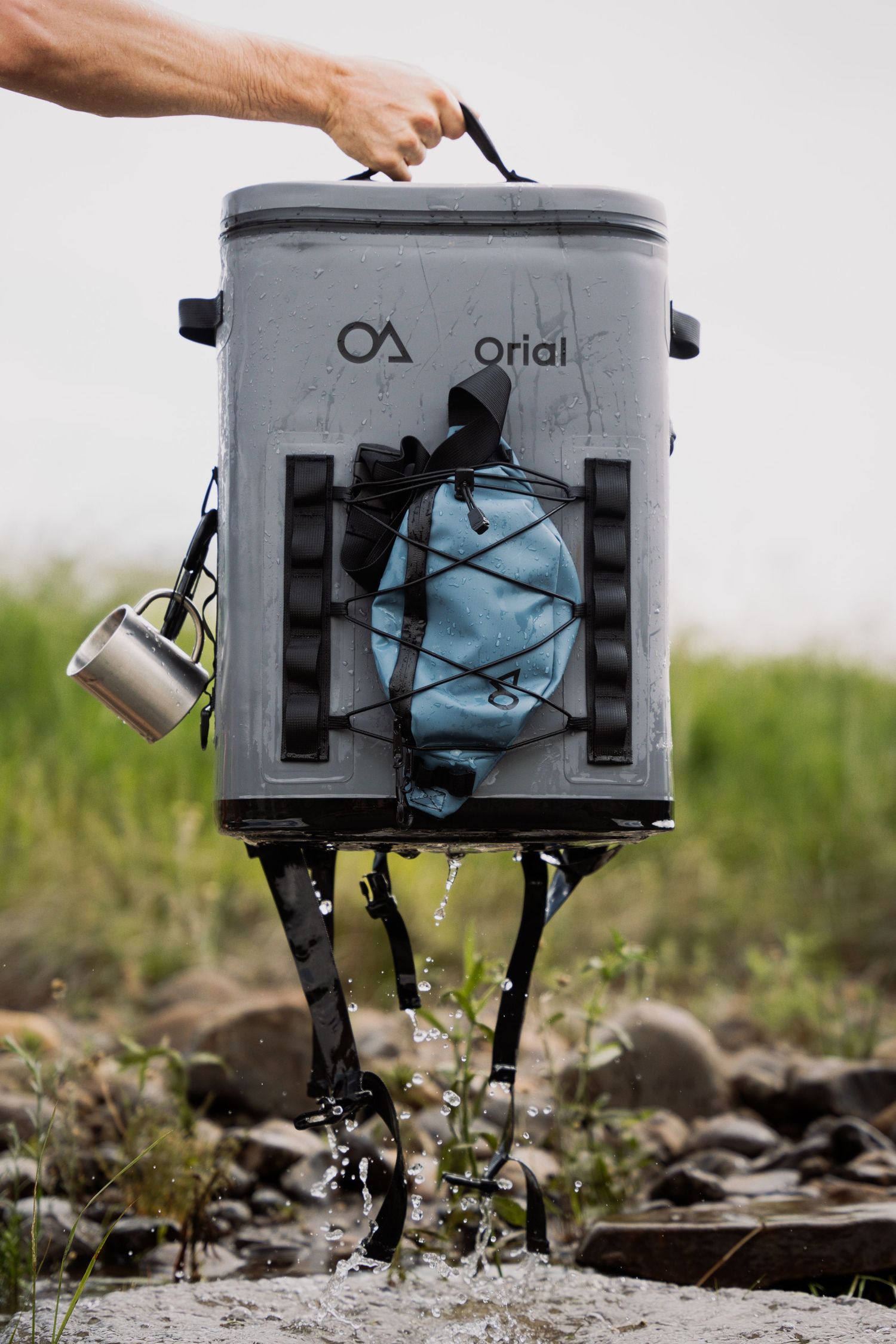 Grey waterproof camera housing splashing through puddles on rocky terrain, demonstrating durability testing.