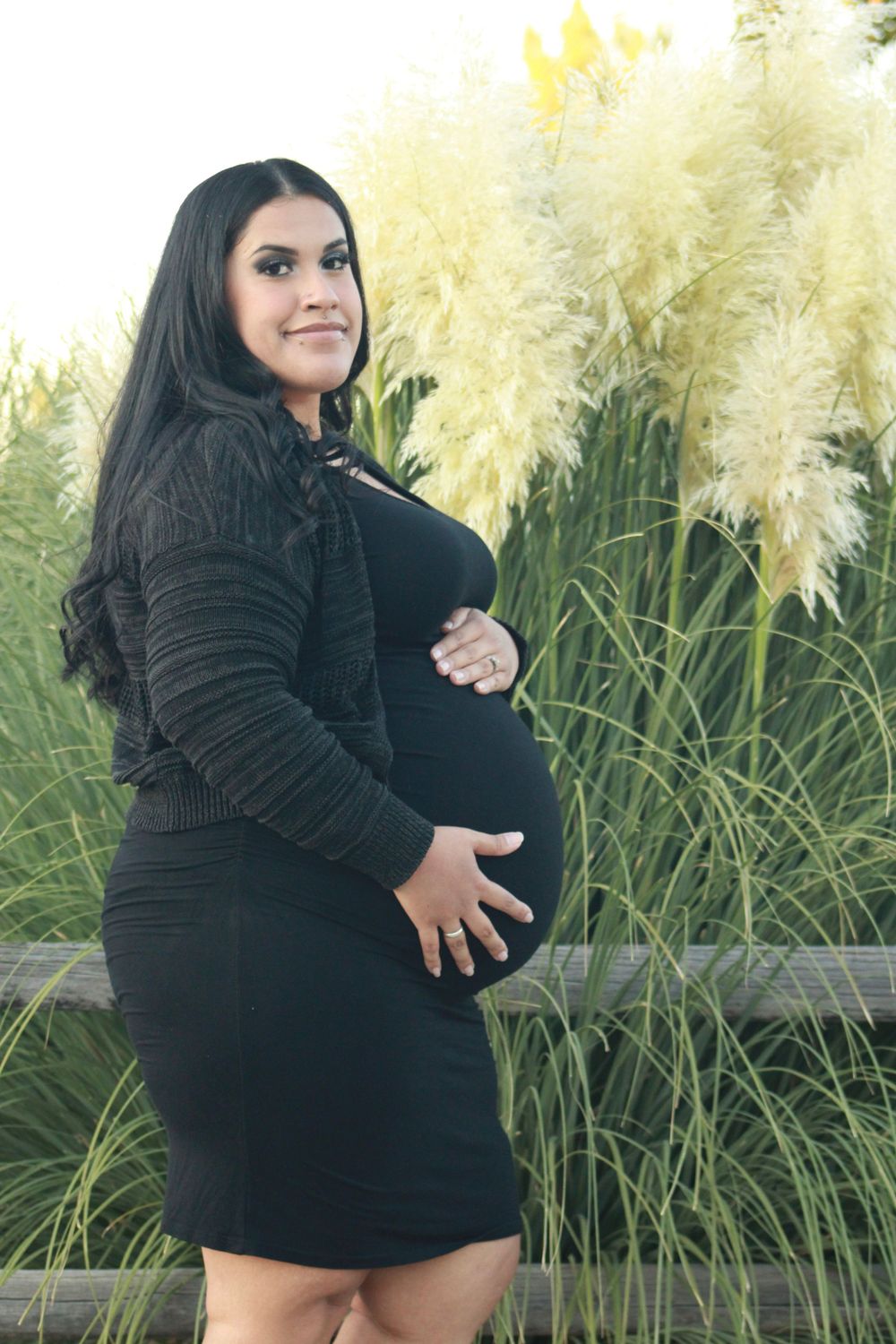Maternity portrait against ornamental grasses in natural lighting.