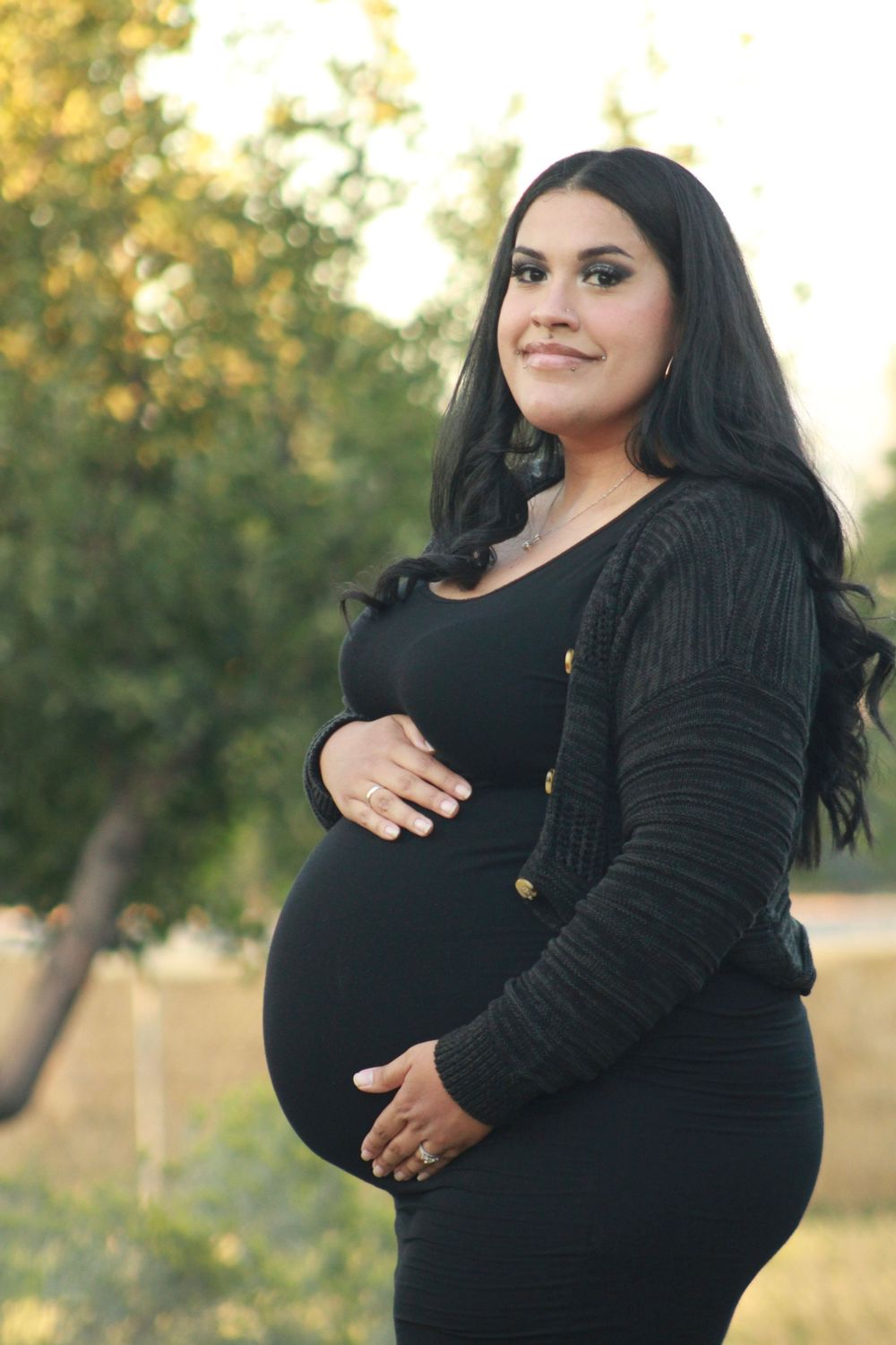 Side view maternity portrait showing pregnancy silhouette in black dress.