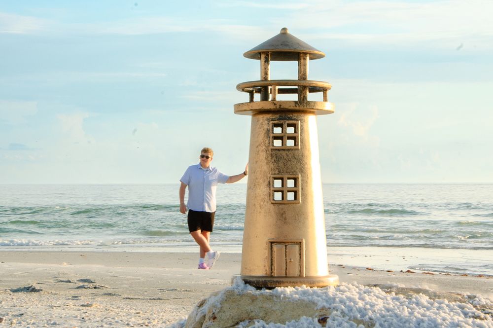 photoshopped senior portrait of boy leaning on lighthouse in New Port Richey