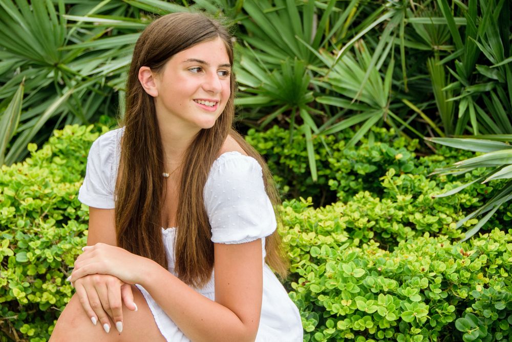senior portrait of girl sitting by palms in New Port Richey