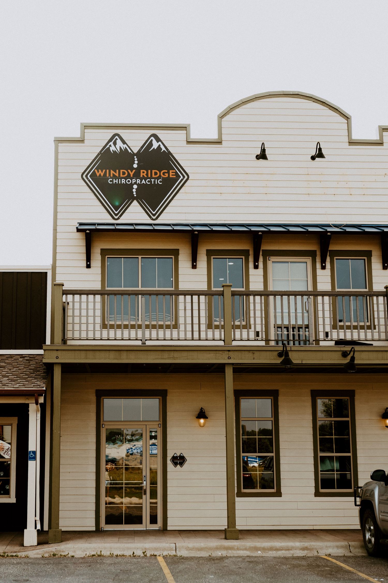 Two-story rustic building with wooden porch and 'Wind Ridge' signage on a cloudy day.