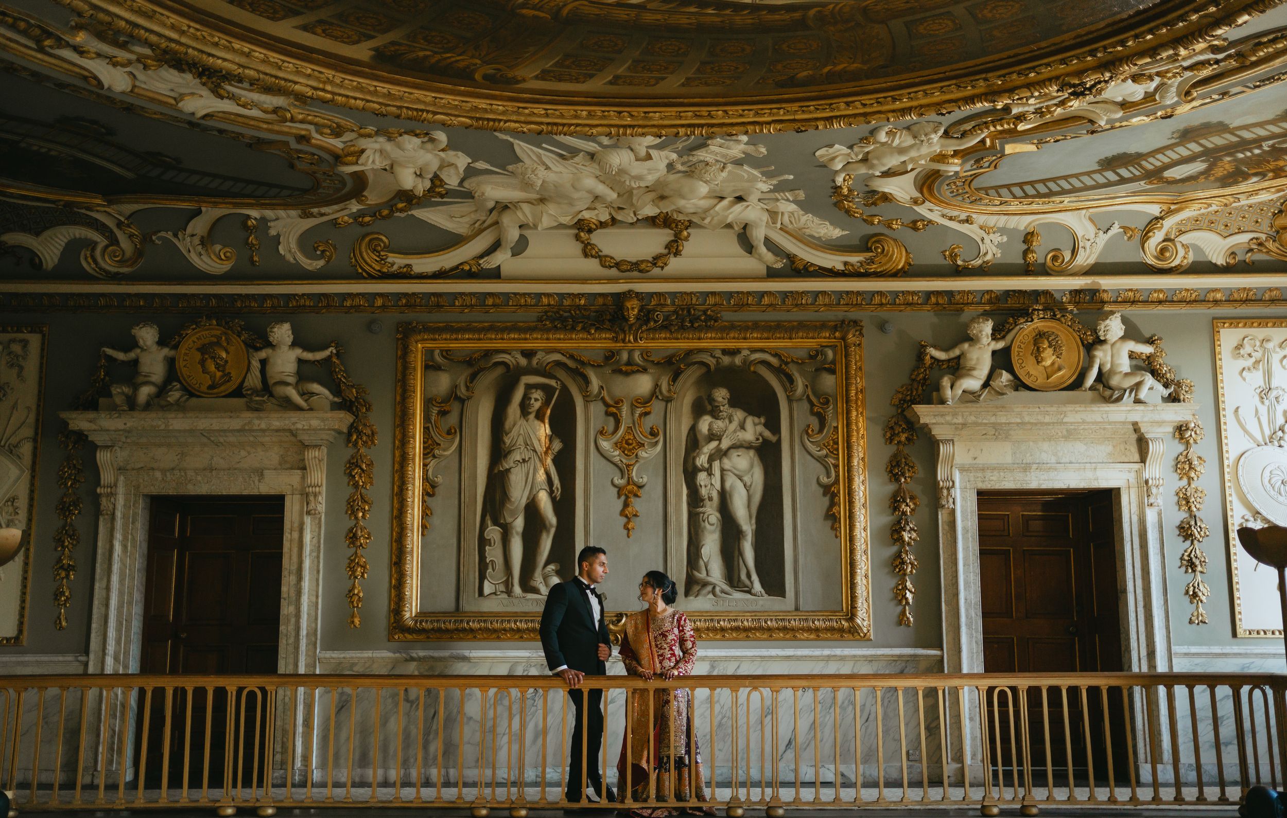 Ornate baroque palace interior with gilded details, frescoed ceilings, and mirrored walls in a grand gallery hall.