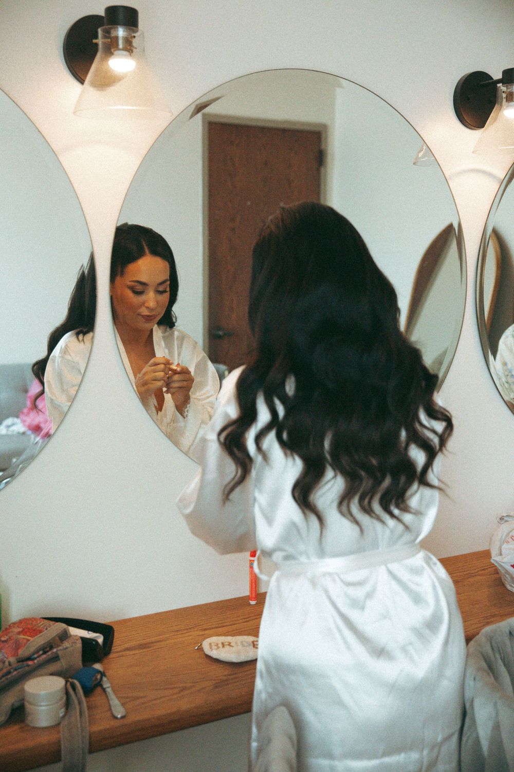 Reflections in salon mirrors show wedding day preparations with white satin robes.