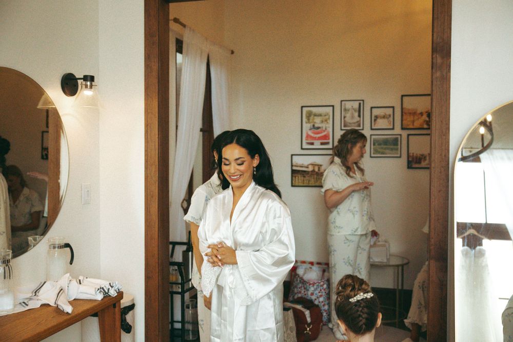Getting ready scene with bride in white robe preparing for wedding day in bridal suite.