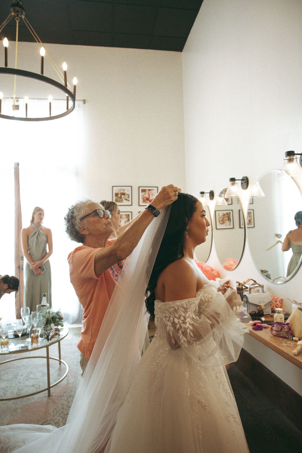 Wedding preparations in a bridal suite with chandelier lighting and vintage decor.