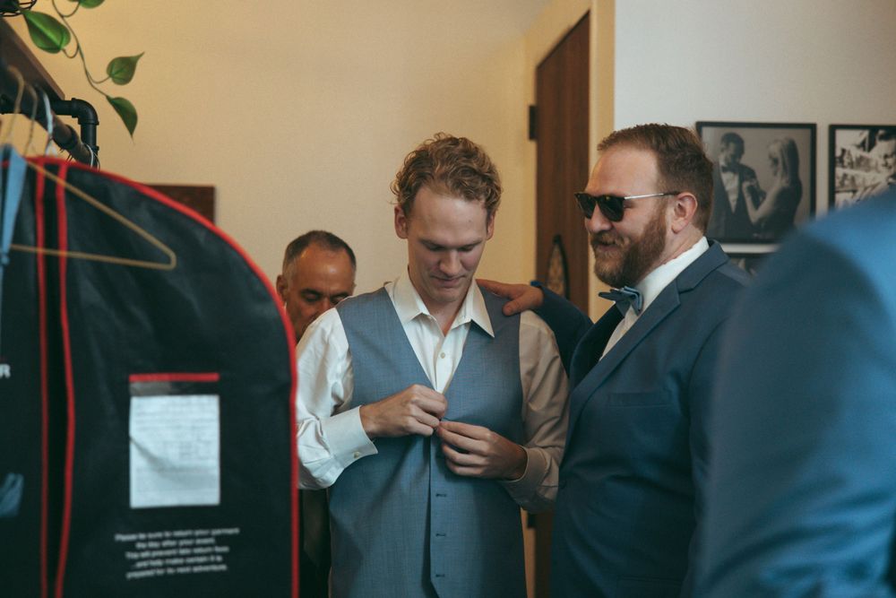 Wedding preparation scene showing men in formal attire getting ready.