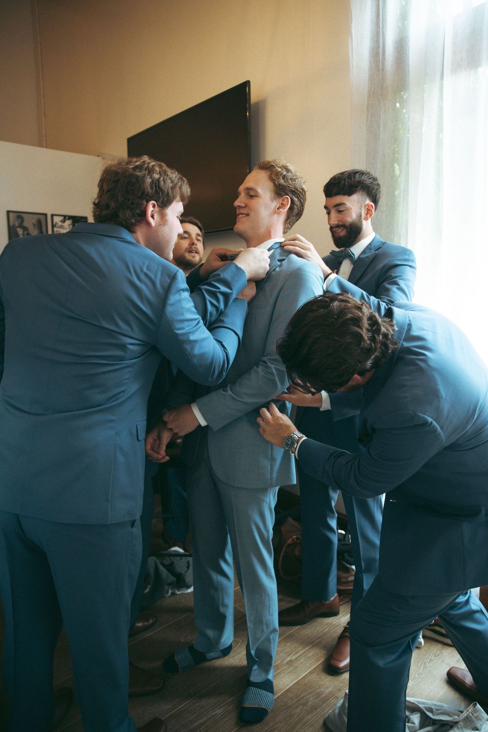 Groomsmen in matching blue suits helping with final wedding day preparations.