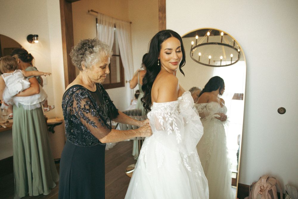 Wedding preparations showing final adjustments being made to a beautiful lace bridal gown.