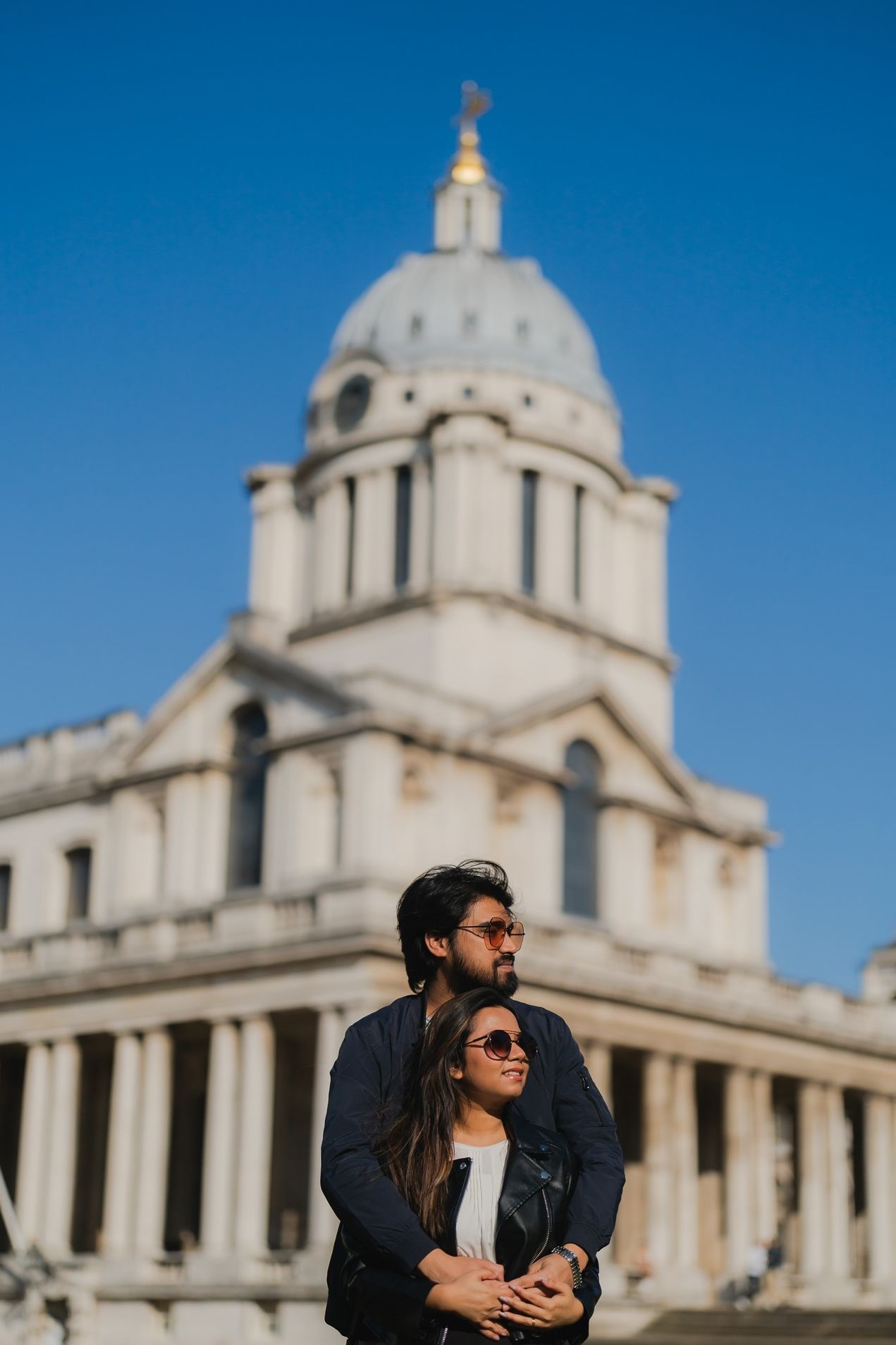 Indian couple walking together, bride in red saree and groom in black suit.