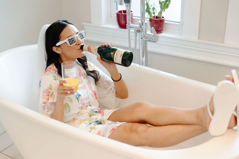 A woman is sitting in a bathtub with a glass of wine.