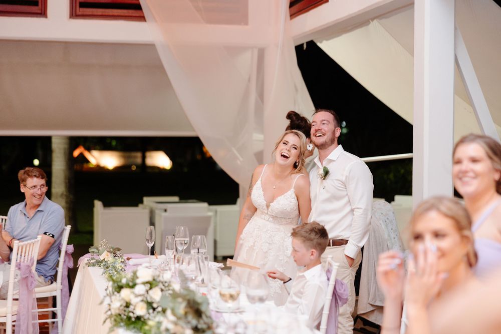 A bride and groom laughing at their wedding reception.