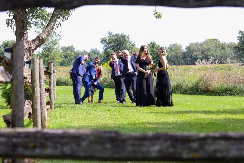 A group of bridesmaids and groomsmen walking through a fence.