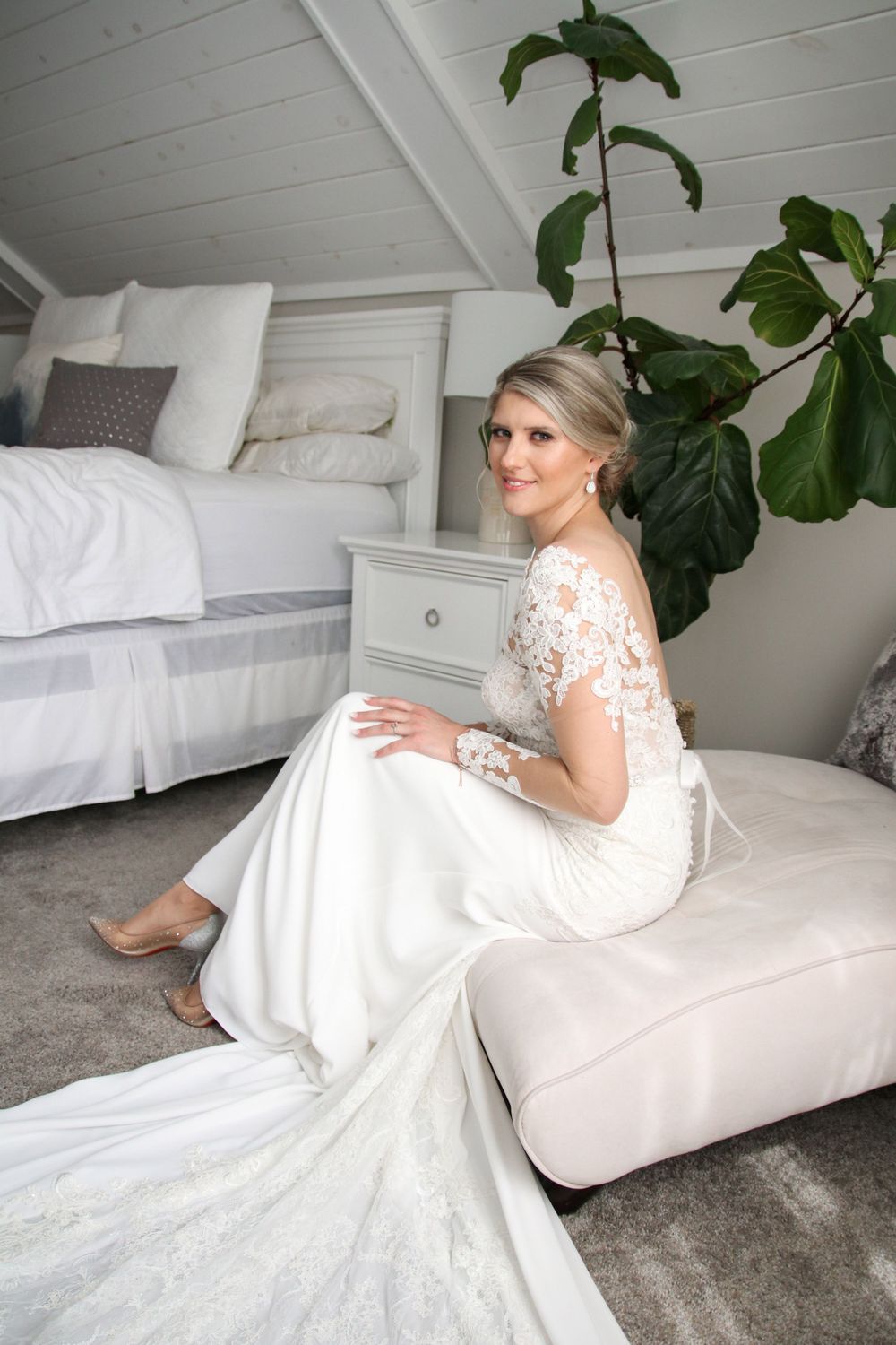 A bride sitting on a bed in a bedroom.