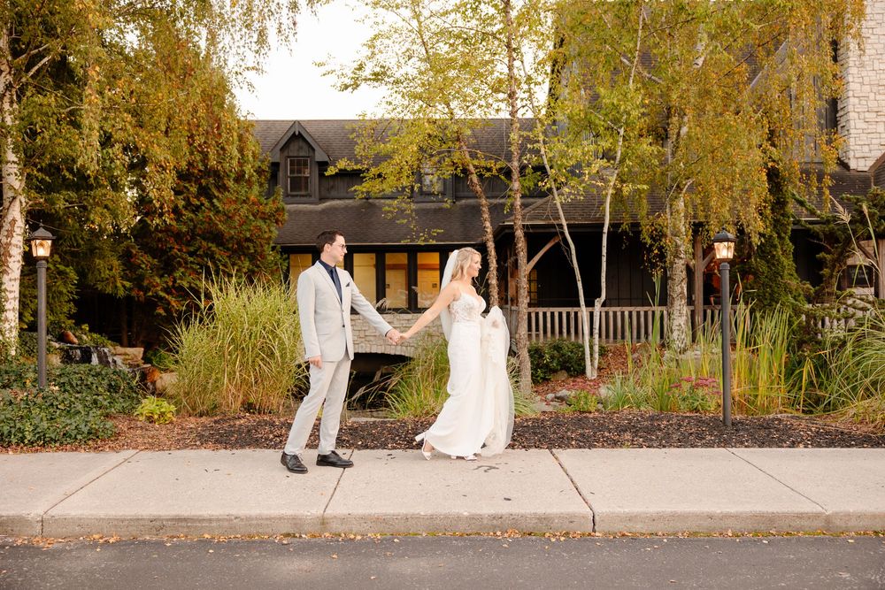 A couple walks along a path under golden autumn trees in a romantic outdoor setting.