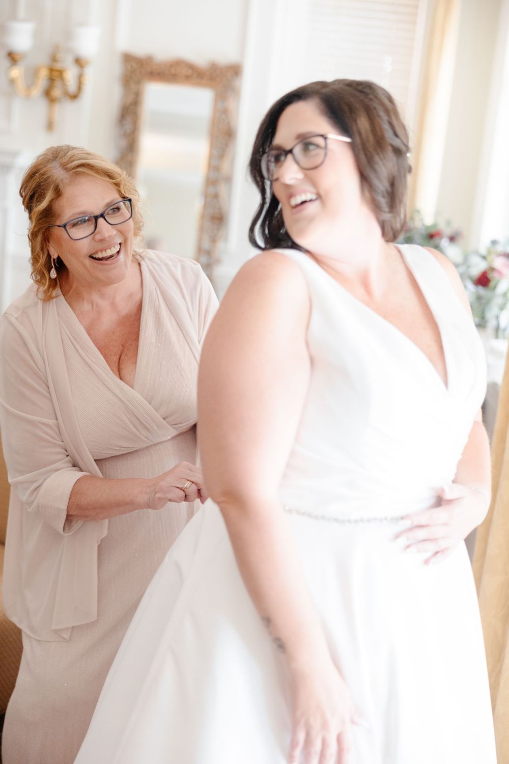 A bride getting ready in a hotel room with her mother.