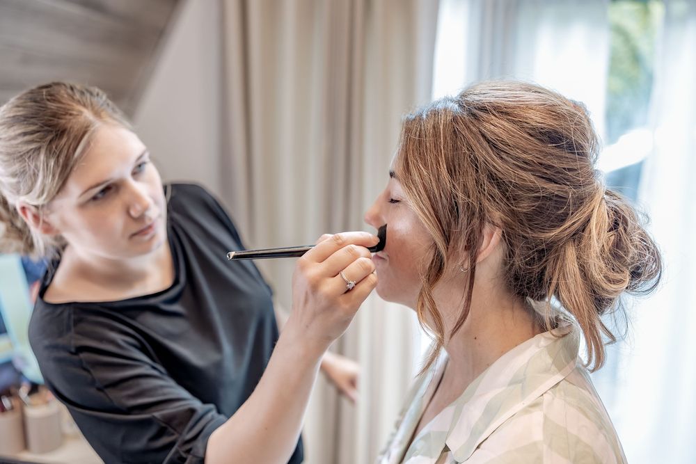 Unobtrusive wedding photography of bride getting make up done during bridal preparations.