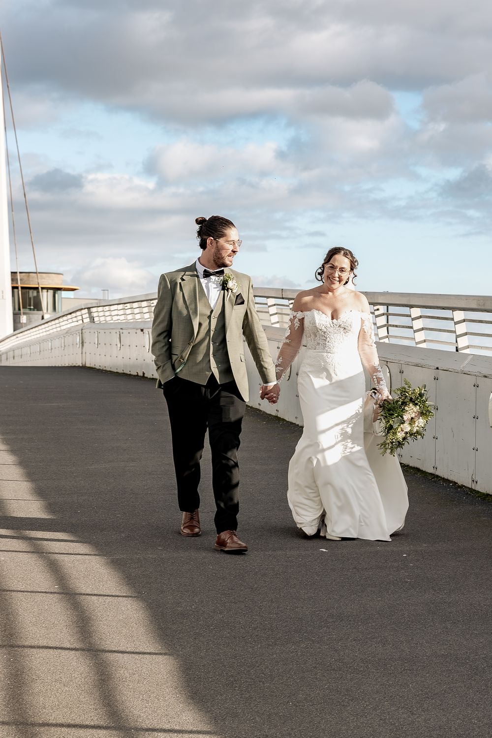 A natural documentary wedding moment as bride and groom take a walk hand in hand along the river.