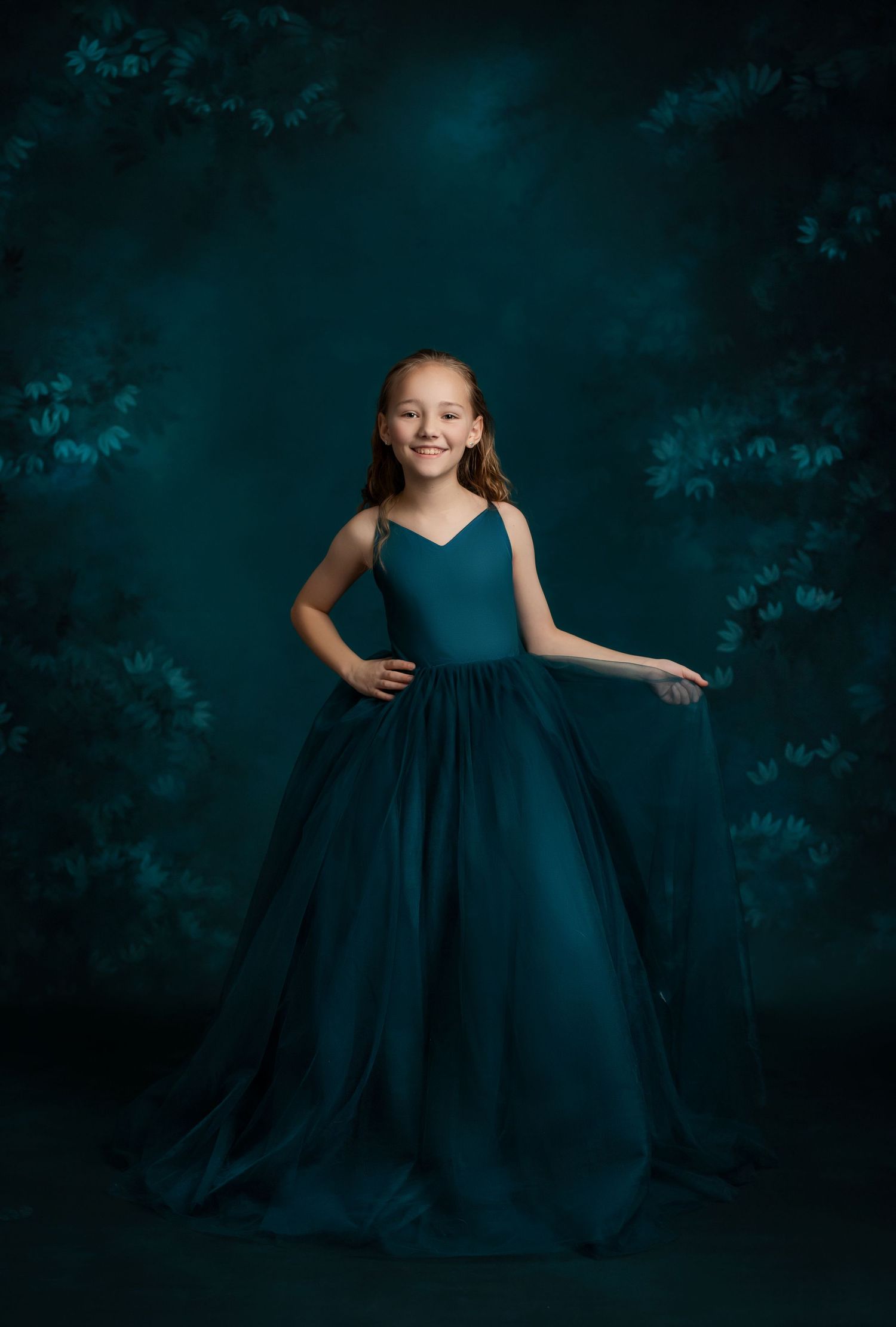 Dramatic portrait in flowing navy ball gown against dark atmospheric background.