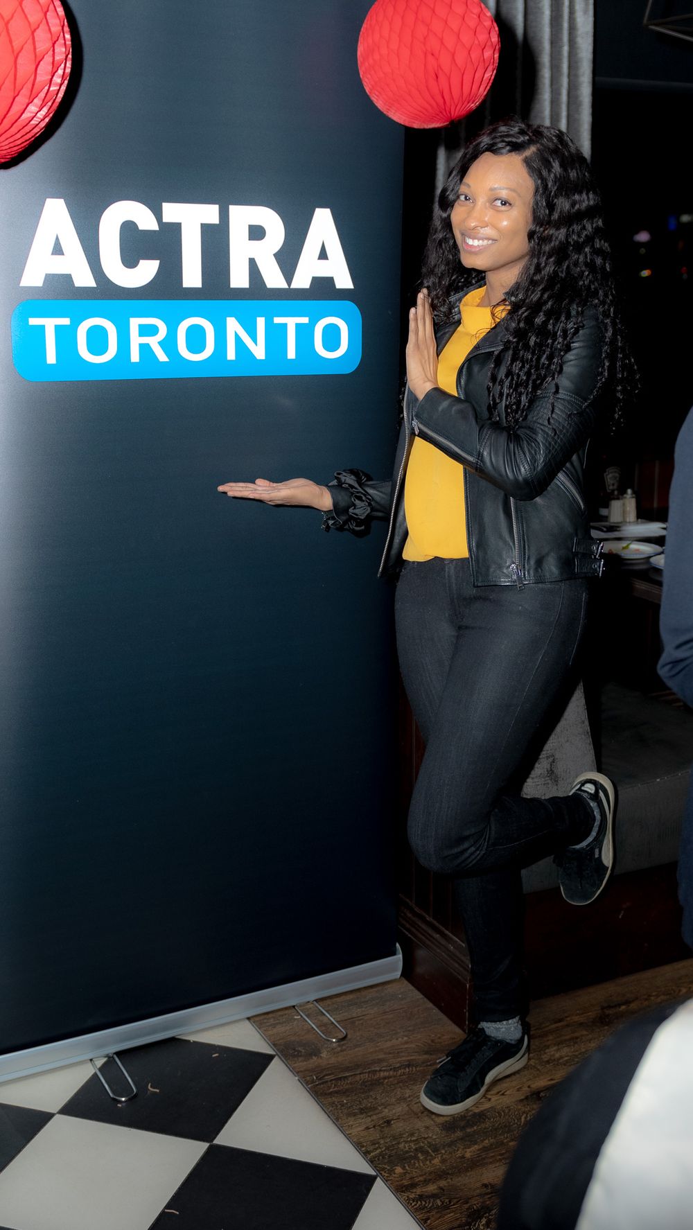 Person posing at ACTRA Toronto event wearing black leather jacket and yellow top.