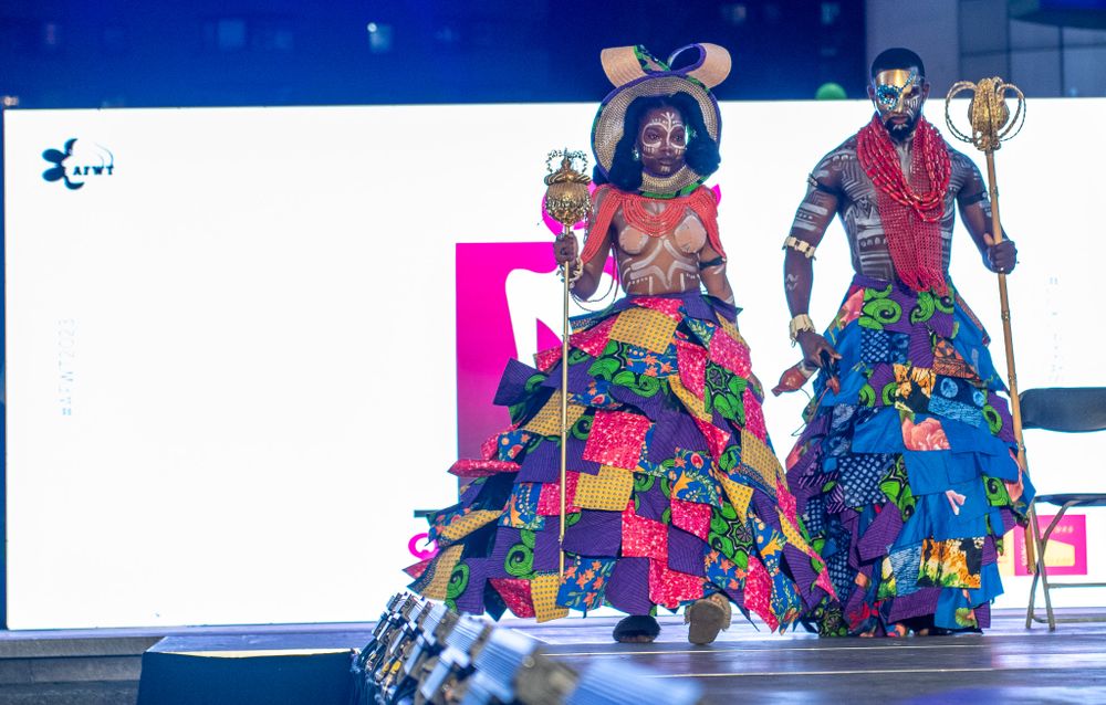 Models displaying vibrant patchwork outfits in multicolor designs on fashion runway.
