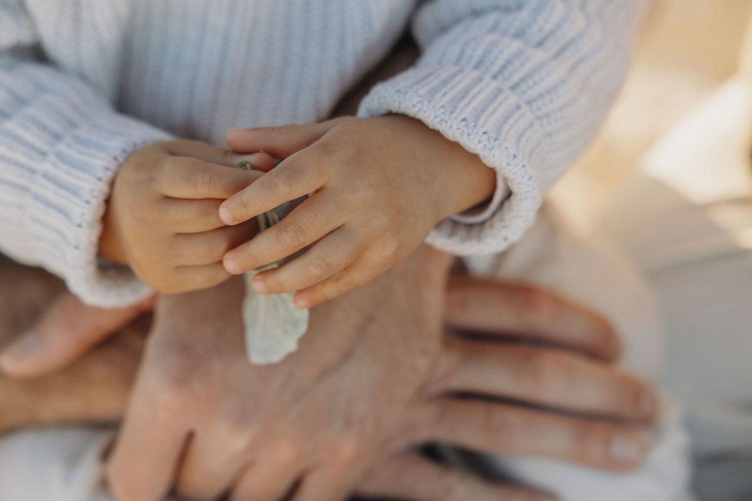 close up detail of toddler hands with beach sand