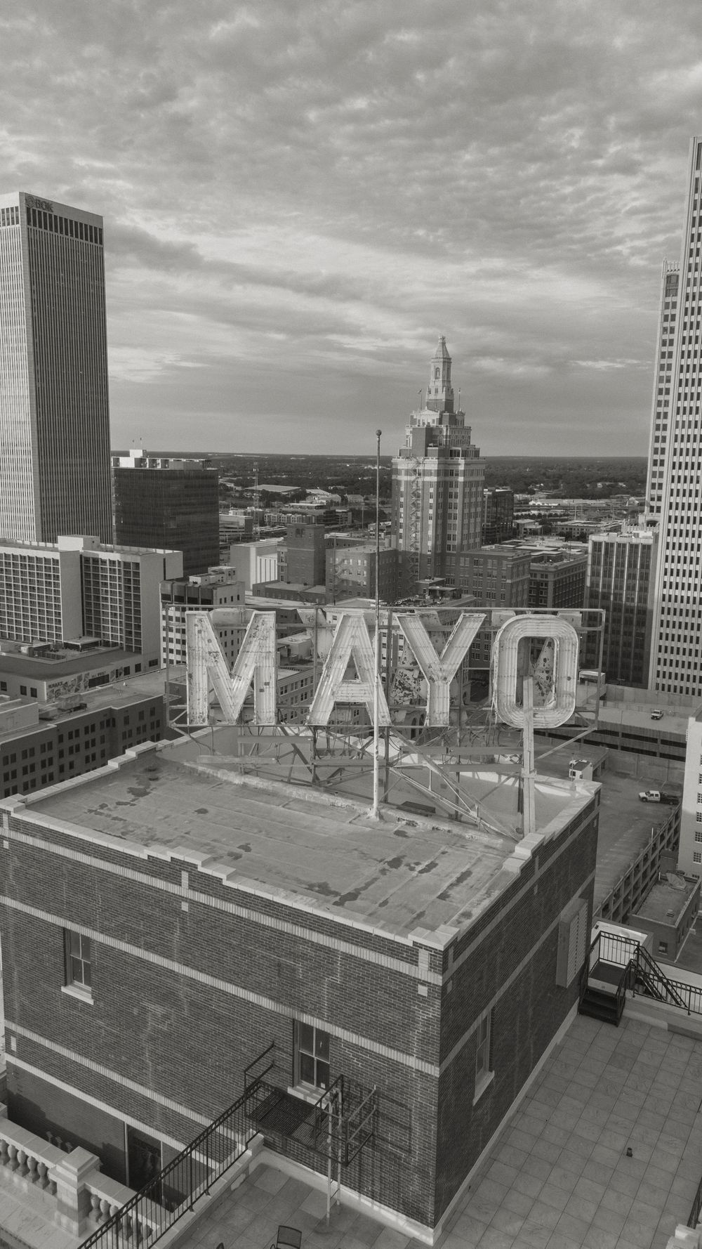 Black and white aerial view of the historic Mayo Hotel rooftop sign in downtown Tulsa, Oklahoma skyline.