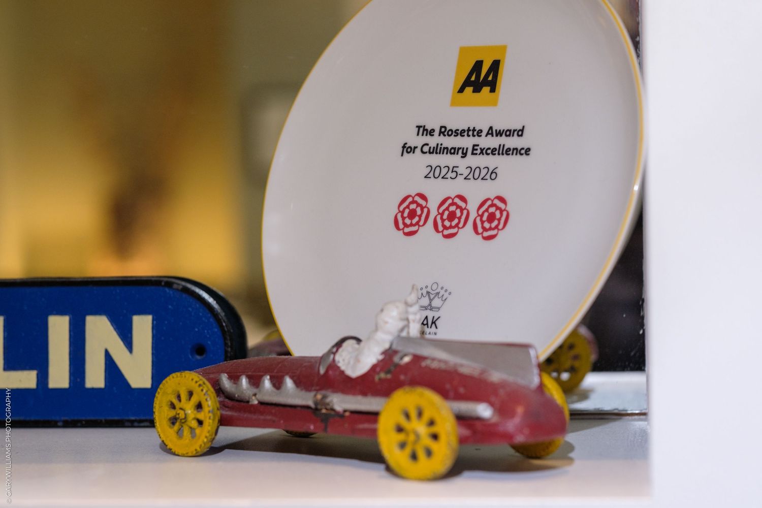 AA Rosette Award for Culinary Excellence 2025-2026 displayed with a vintage toy racing car and Michelin sign.