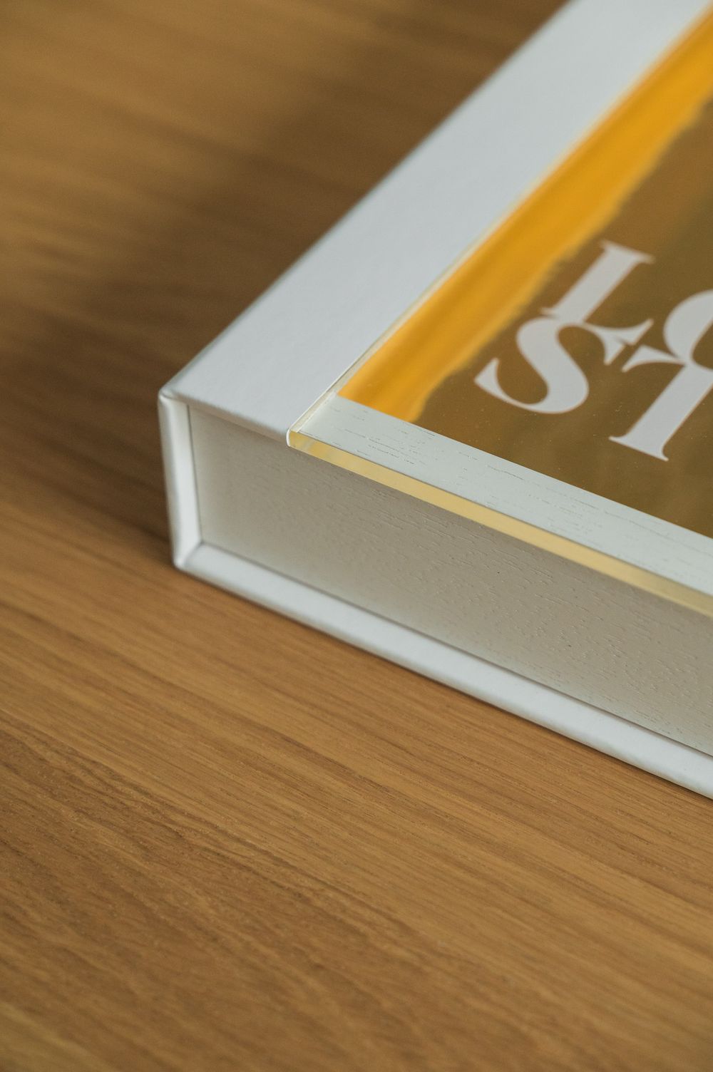 White hardcover Love Stories photo book on a wooden surface, showing spine and corner detail.