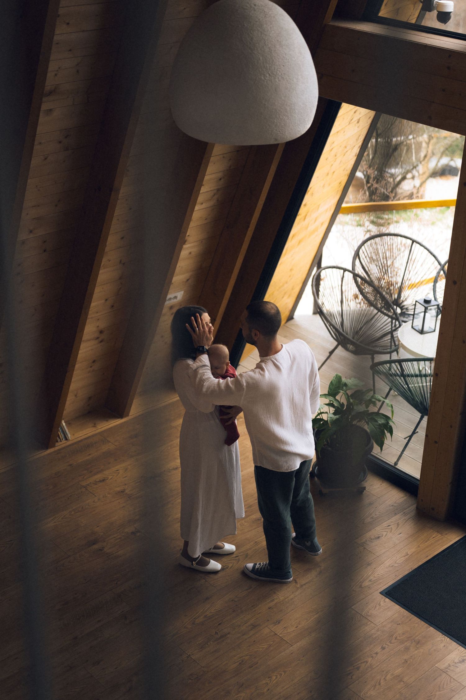 Couple dancing together in a modern A-frame cabin interior with wooden beams and large windows.