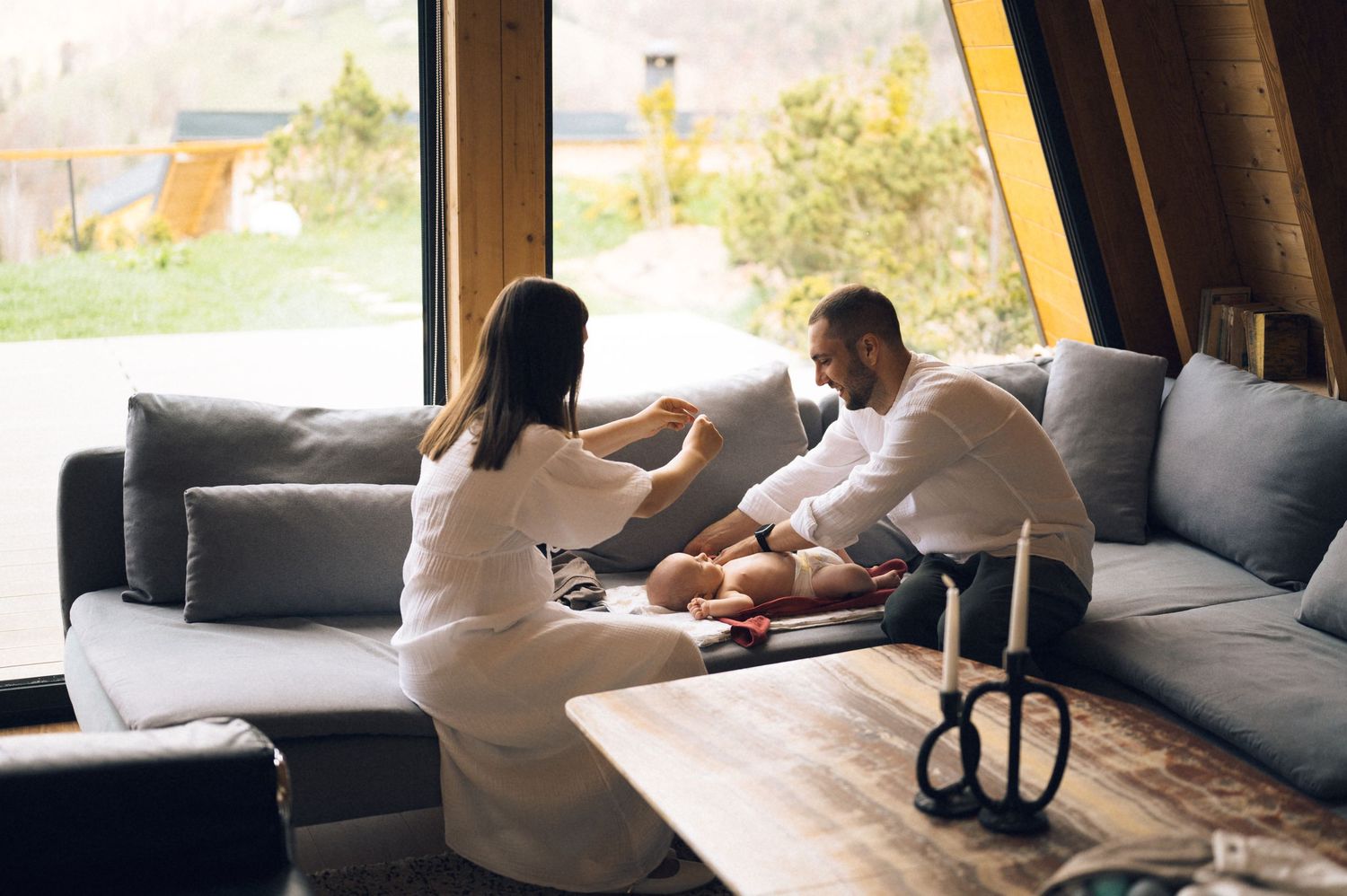 Couple relaxing together on a gray sofa in a modern living room with large windows and mountain views.