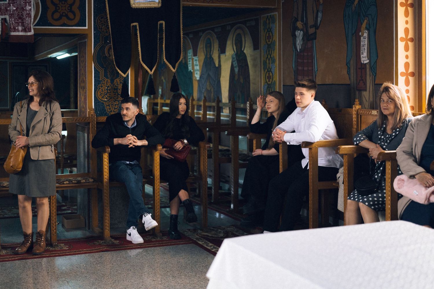 People sitting in wooden pews inside a decorated church during a religious gathering or ceremony.